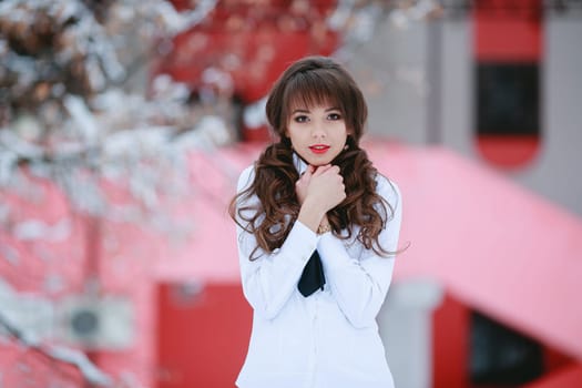 Woman,lady,student,model with cure,white smile,white blouse,grab,embrace herself hands,creative background,snowflackes,trees with snow,curly hair,red lips.Japan.China.Surprised girl stand with open mouth,red lips in winter beautiful park,pink castle