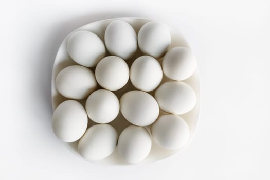 White eggs on a plate on a light background.