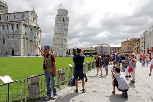 Tourists take pictures in front of the famous Leaning Tower of Pisa in Italy