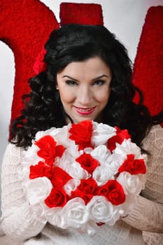 Valentine's day holiday.Attractive,cheerful,smiling,beautiful brunette,with curly,dark hair,healthy,white,cute smile girl,woman with beautiful bouquet of flowers,white,red roses in the photo-studio.