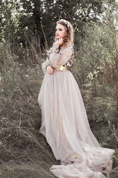 Beautiful smiling thinking girl with long white dress with loop standing outdoors in summer