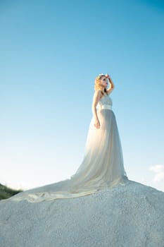 Beautiful smiling thinking girl with long white dress with loop standing outdoors in summer