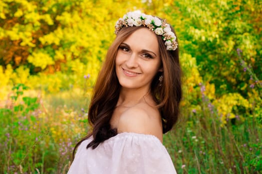 Portrait of pretty attractive nice smiling girl with wreath of flowers in summer field