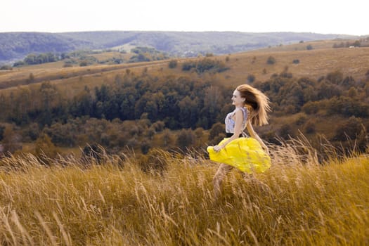 Happy smiling enjoying summer nature girl running in summer meadow sunny field full wheats, flowers. Girl in summer light dress running in hills, mountains, fields.
