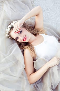 Smiling cute attractive girl in white dress and wreath of white beautiful flowers. Beautiful healthy whitesmile. Top view. Top from above