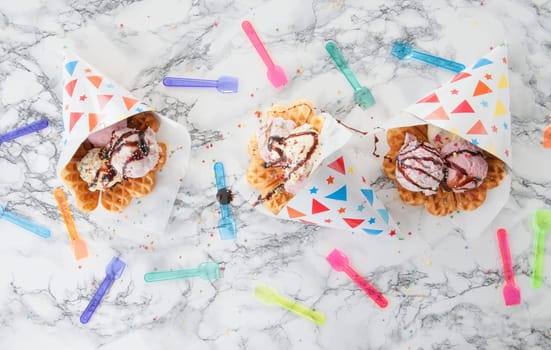 Different types of ice cream with sprinkles in fresh waffles