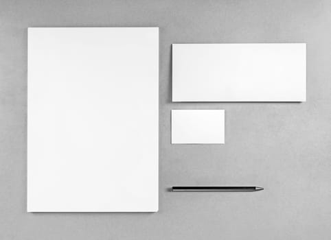 Blank stationery template for placing your design. Photo of blank stationery set. Blank letterhead, business cards, envelope and pencil. Mockup for branding identity. Top view. Grayscale image.