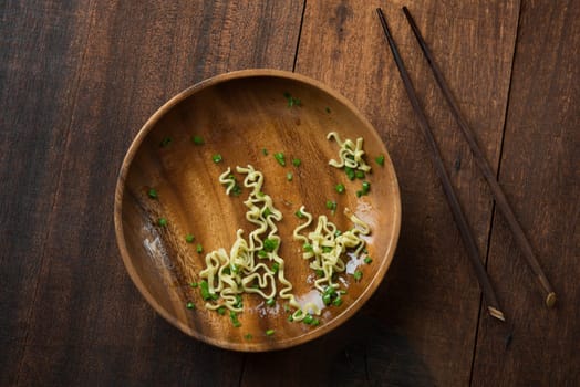 Top view leftover food Japanese ramen dried noodles with chopsticks on rustic wooden table.
