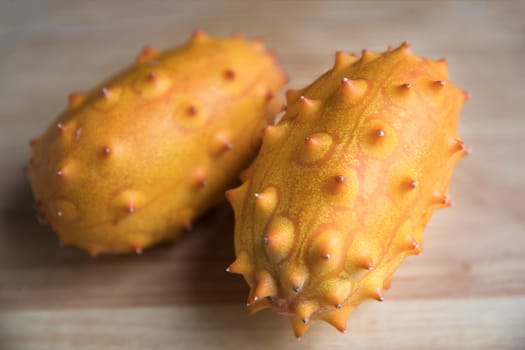 Two whole kiwano fruits on wodden surface