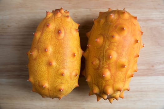 Two whole kiwano fruits on wodden surface from high angle.