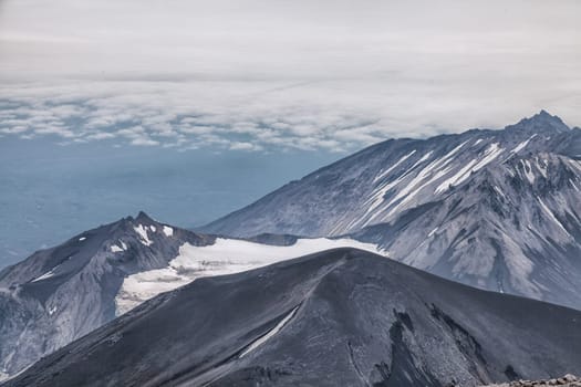 Mountains and volcanoes. Beautiful landscape of Kamchatka Peninsula: summer panoramic view of Mountain Range Vachkazhets, mountain lake and clouds in blue sky on sunny day. Eurasia, Russian Far East, Kamchatka Region.