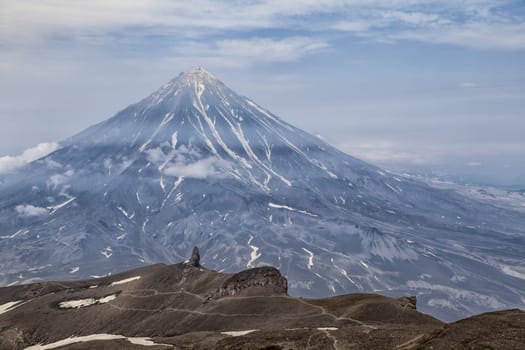 Mountains and volcanoes. Beautiful landscape of Kamchatka Peninsula: summer panoramic view of Mountain Range Vachkazhets, mountain lake and clouds in blue sky on sunny day. Eurasia, Russian Far East, Kamchatka Region.