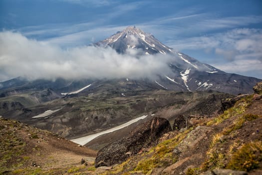 Mountains and volcanoes. Beautiful landscape of Kamchatka Peninsula: summer panoramic view of Mountain Range Vachkazhets, mountain lake and clouds in blue sky on sunny day. Eurasia, Russian Far East, Kamchatka Region.