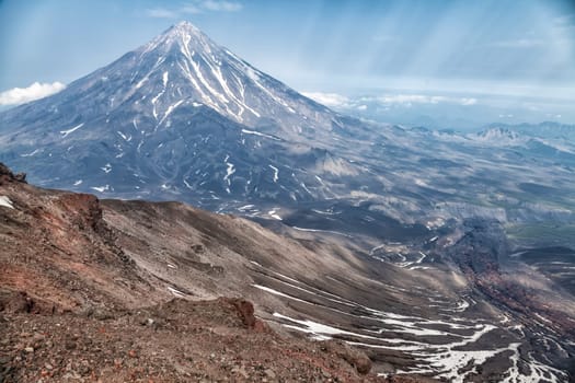 Mountains and volcanoes. Beautiful landscape of Kamchatka Peninsula: summer panoramic view of Mountain Range Vachkazhets, mountain lake and clouds in blue sky on sunny day. Eurasia, Russian Far East, Kamchatka Region.