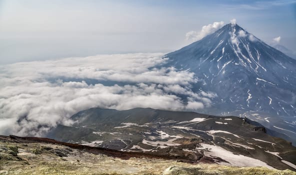 Mountains and volcanoes. Beautiful landscape of Kamchatka Peninsula: summer panoramic view of Mountain Range Vachkazhets, mountain lake and clouds in blue sky on sunny day. Eurasia, Russian Far East, Kamchatka Region.