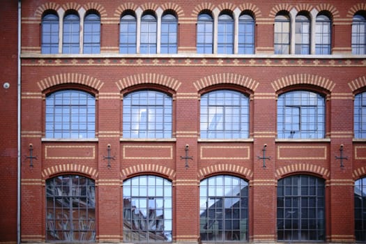The exterior façade of a brick school building with large lead windows.