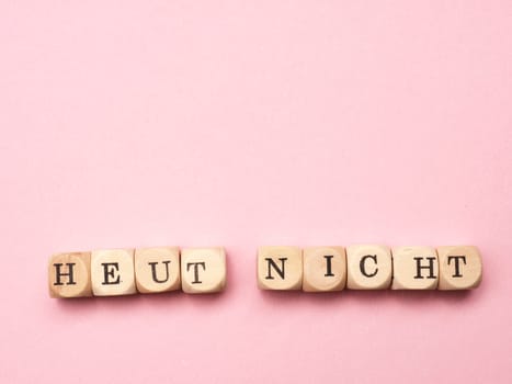 German words not today on wooden dices on a pink background with space for text or image