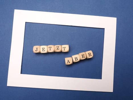 German words Start now on wooden dices on a blue background