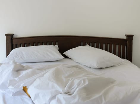 Morning view of an unmade bed in white bedroom