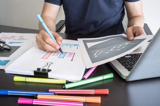 Business, office concept. Man writing graph on paper with color pen.