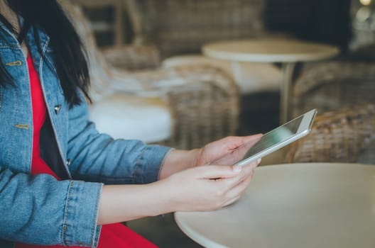 Close-up young woman using tablet with financial graph screen in coffee shop. Vintage Filter