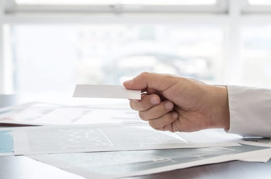 Close-up businessman holding empty business card. Business, office concept.