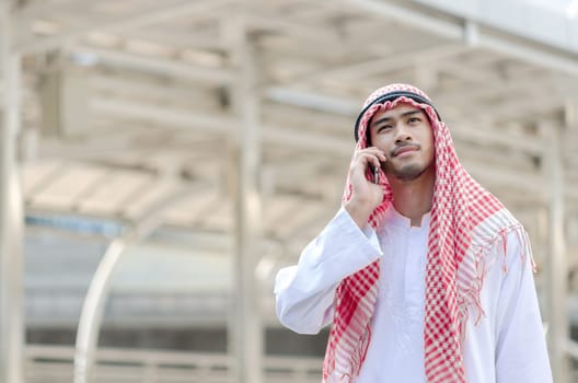 Young Arab businessman using mobile phone while walking in the city. business travel and mobile roaming concepts.