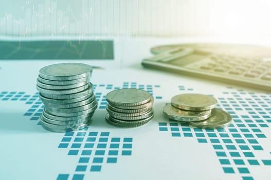 Coin stacks and calculator on paper of financial graph. Graphics icons, worldwide stock exchanges. Business concept. Color filter.