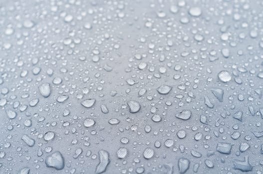 Water droplets on grey fiber waterproof fabric. abstract background.
