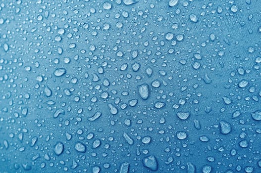 Water droplets on blue fiber waterproof fabric. abstract background.