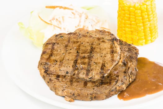 Grilled rib eye steak, corn on the cob and salad close up
