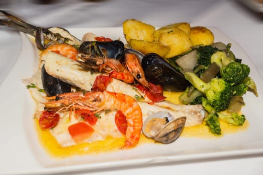 Various seafood,sea bream,mussels and prams on a white plate.