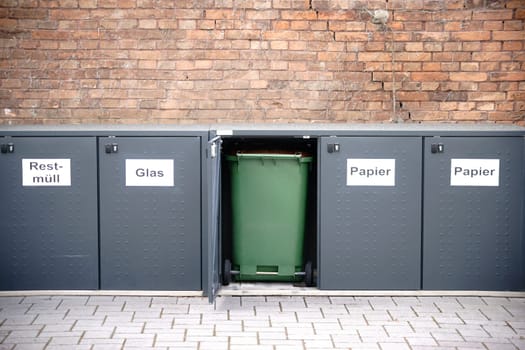 Garbage cans arranged in a row are placed in lockable metal boxes.