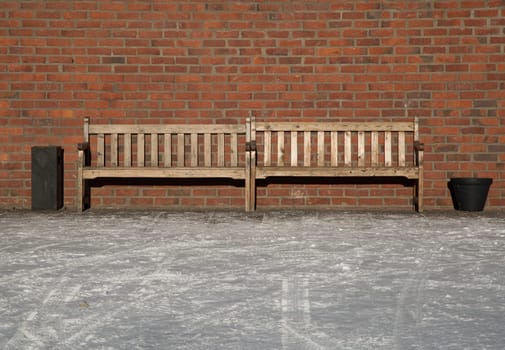 Pair of Benches by brick wall.