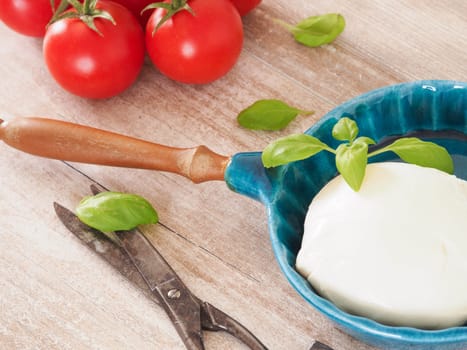 Fresh organic mozzarella with basil and tomatoes in a kitchen