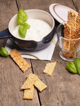Organic cracker with sesame and a tasty garlic dip on a rustic wooden table