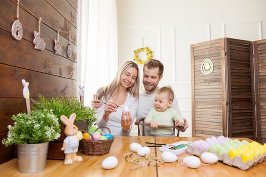 Easter concept. Happy and loving mother and father preparing home decoration with their child for Easter holidays