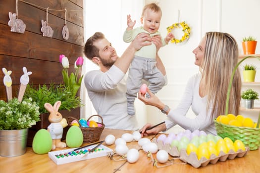 Easter concept. Happy and loving mother and father preparing home decoration with their child for Easter holidays