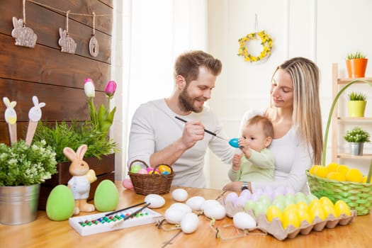 Easter concept. Happy and loving mother and father preparing home decoration with their child for Easter holidays