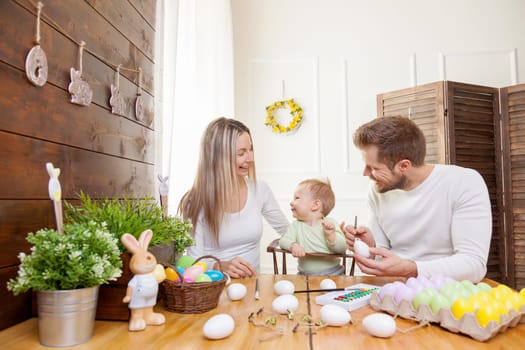 Easter concept. Happy and loving mother and father preparing home decoration with their child for Easter holidays
