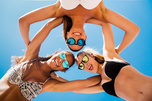 Three beautiful teenage embraced together on the beach