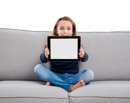 Happy little girl sitting on a couch and working a laptop