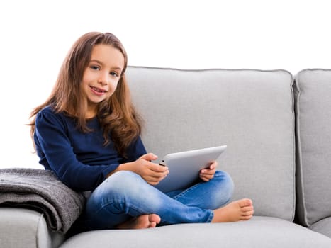 Happy little girl sitting on a couch and working a laptop