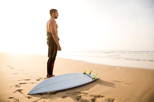 A surfer with his surfboard at the beach