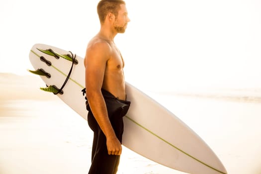 A surfer with his surfboard at the beach