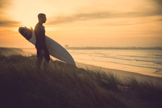 A surfer with his surfboard at the beach