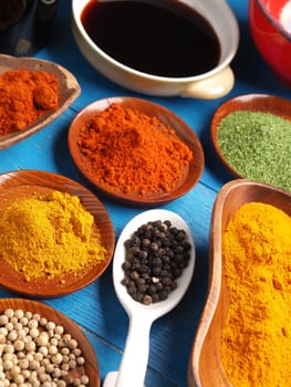 Colorful assortment of spices and herbs on a blue rustic wooden table