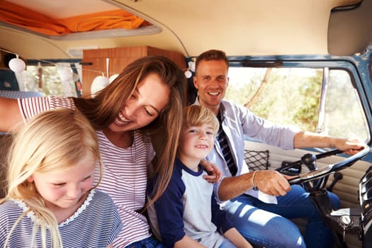 Family sitting at the front of their camper van, dad driving