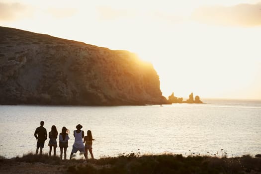 Rear View Of Friends Standing On Cliff Watching Sunset