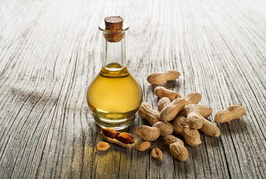 Peanut oil in a glass bottle on a wooden background